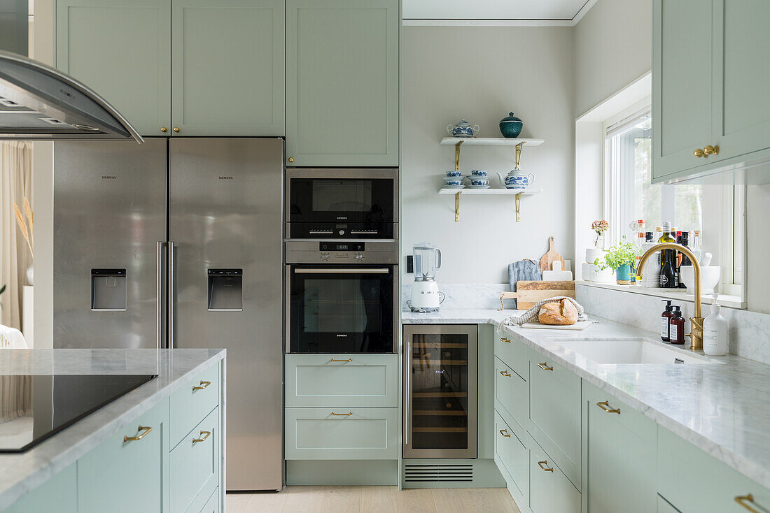 Kitchen in mint green with marble worktop and side-by-side fridge