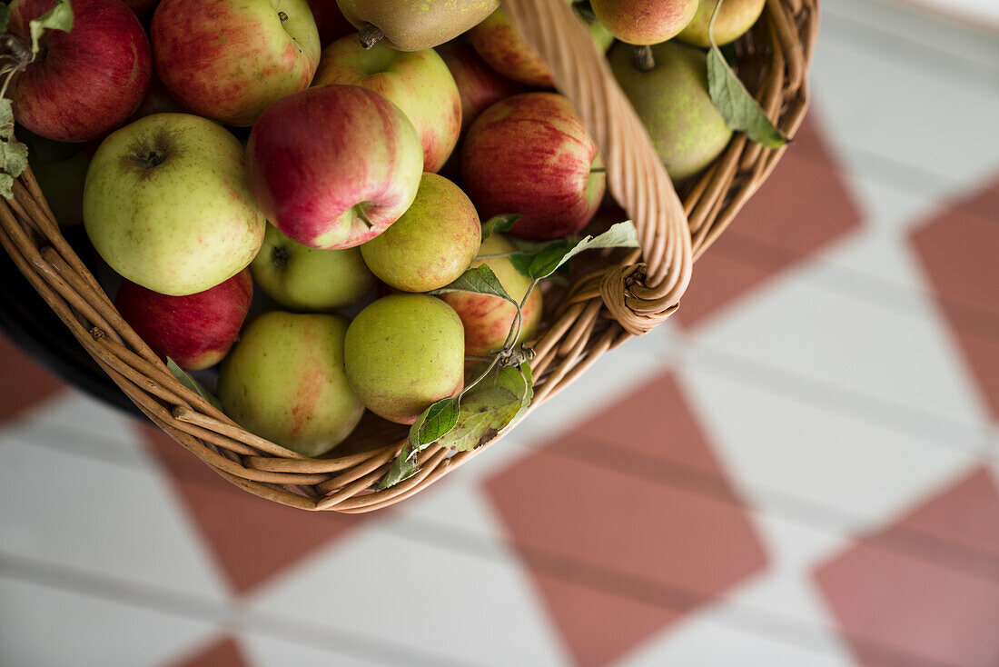 Äpfel im Korb auf kariertem Holzboden