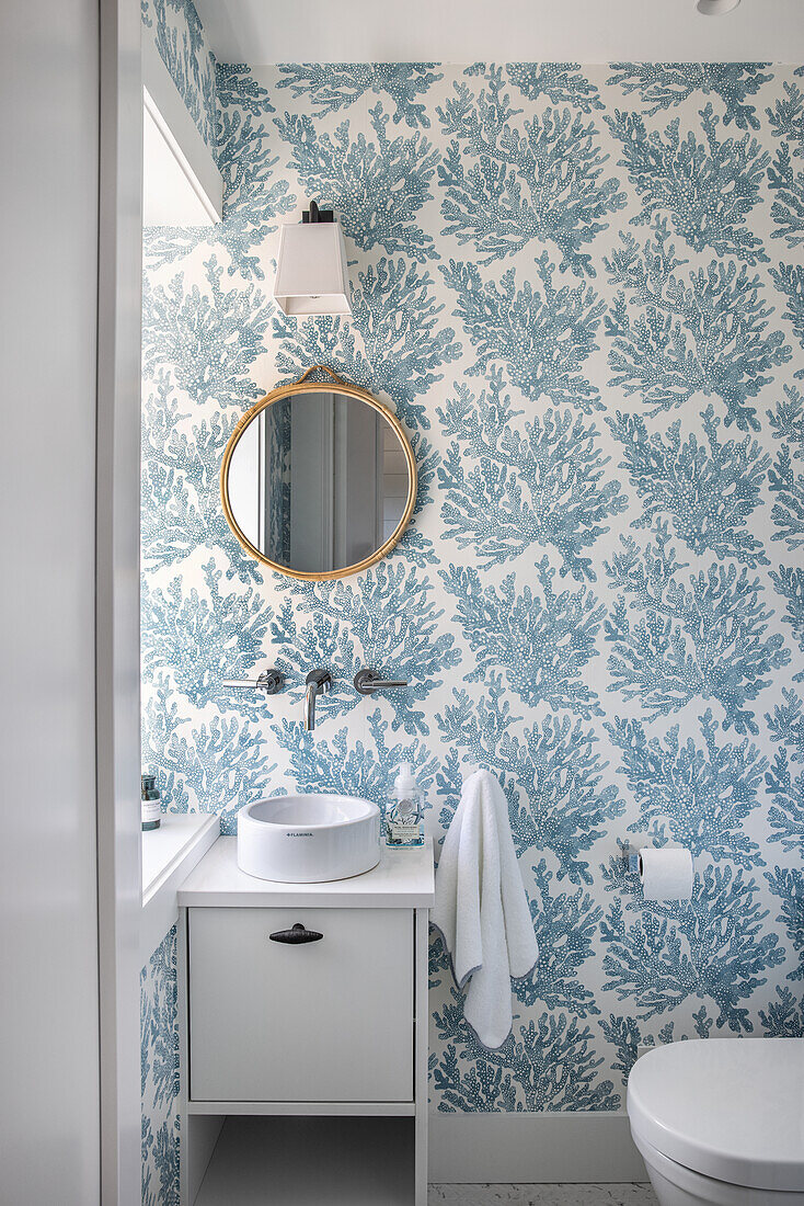 Guest bath with small sink and blue and white wallpaper