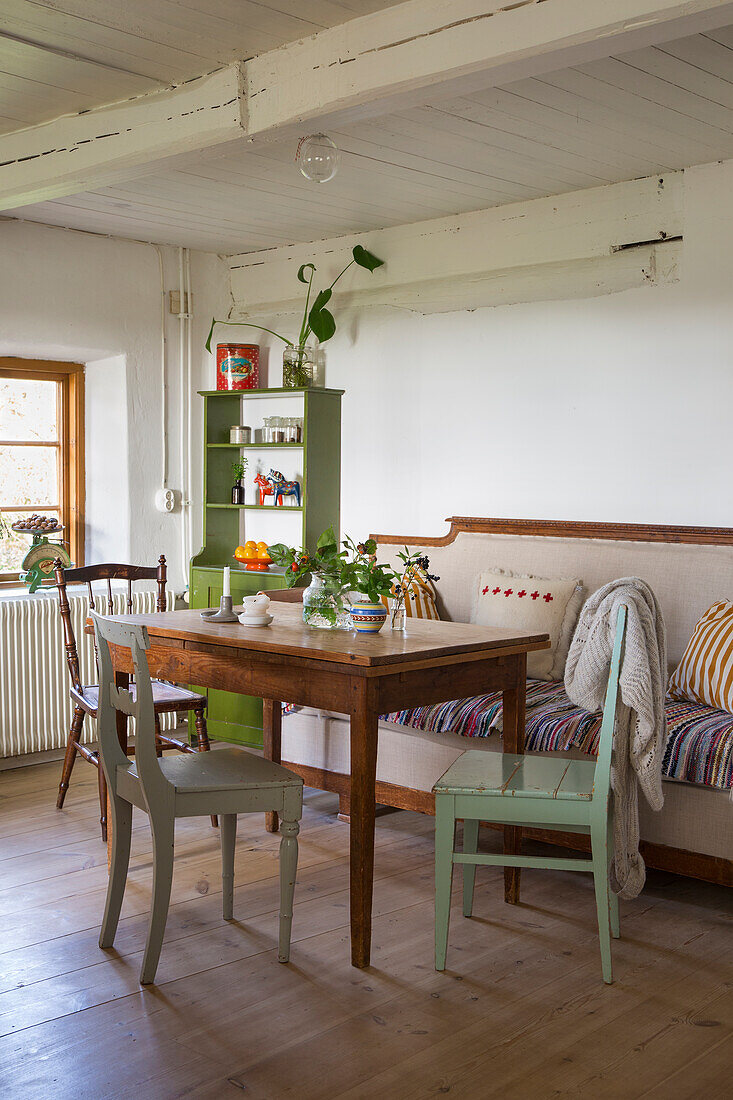 Tisch mit Holzstühlen und Sofa in ländlicher Küche
