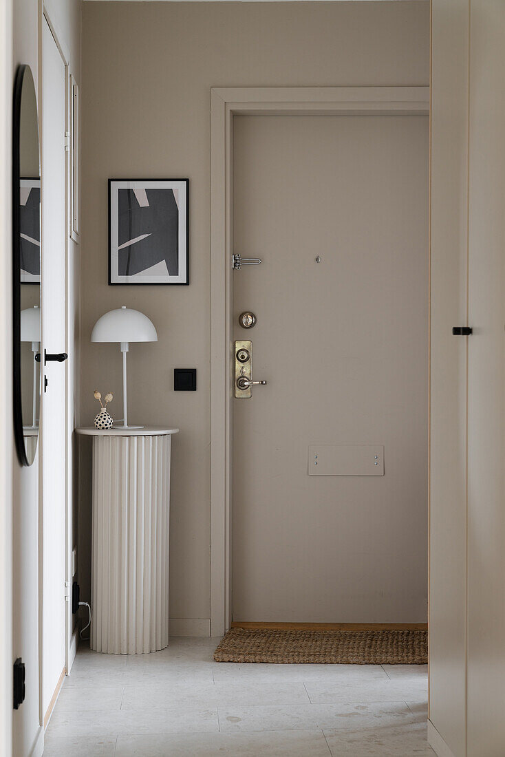 Stele with table lamp in hallway with sand-colored walls