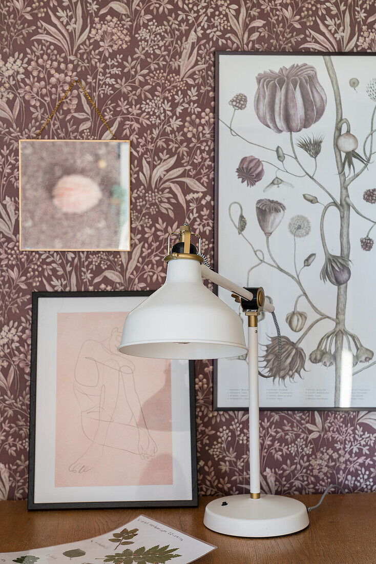 Desk with lamp and pictures, floral wallpaper on the wall