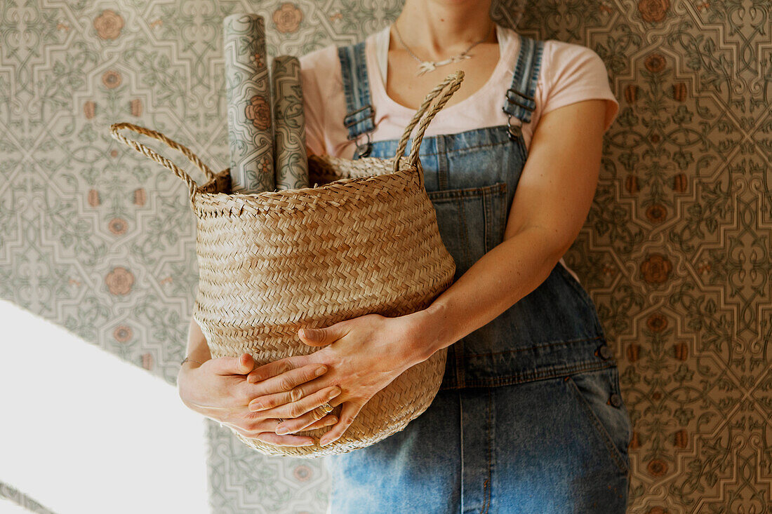 Woman holding basket with wallpaper rolls