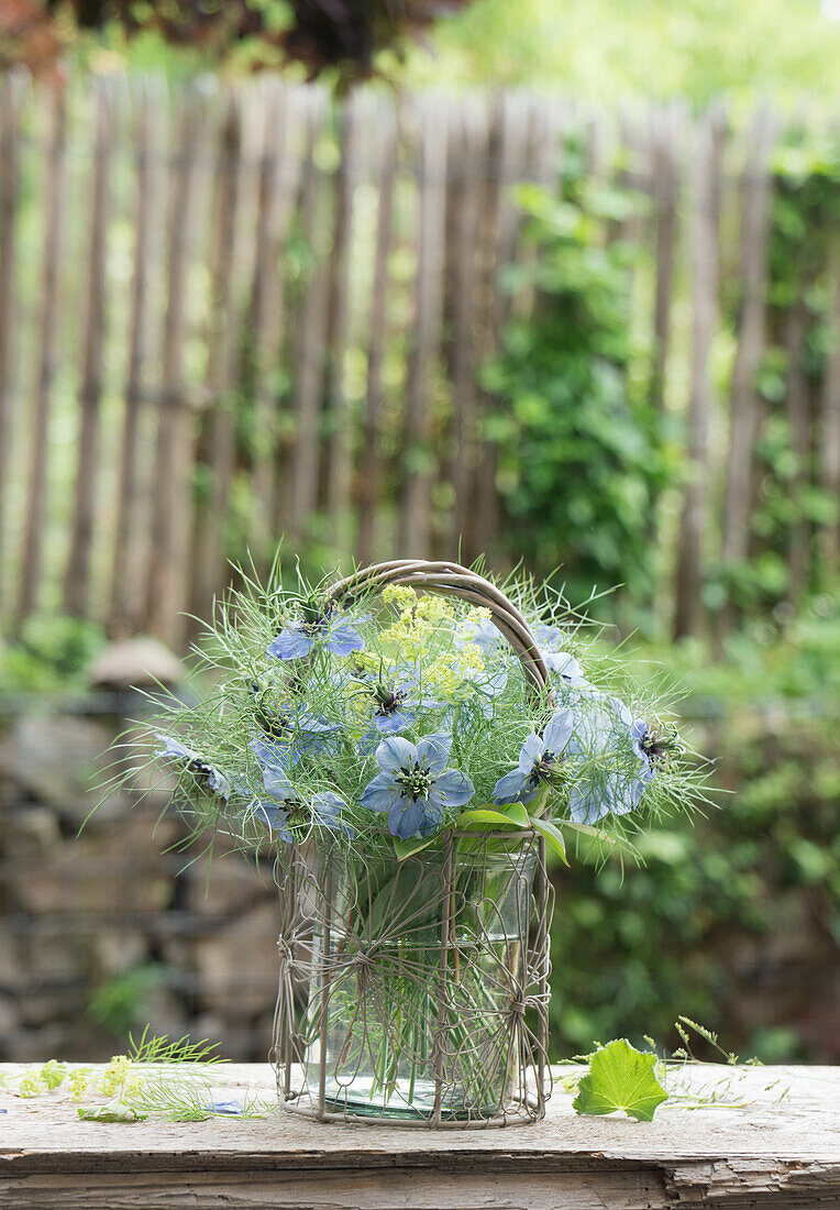 Bouquet of Love in the Mist (Nigella) and lady's mantle (Alchemilla), on wooden table