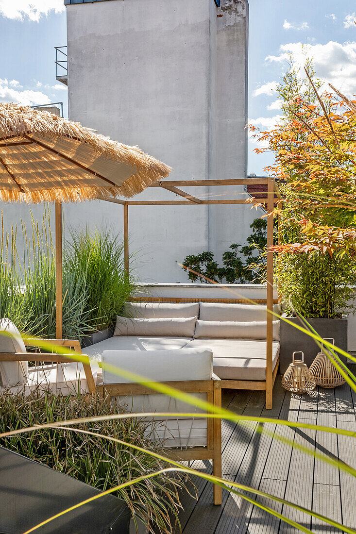 Bed, armchairs, umbrella and planters on the sunny roof terrace