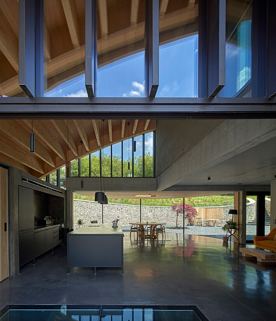 Offene Küche mit Betonboden im Architektenhaus mit gebogenem Dach