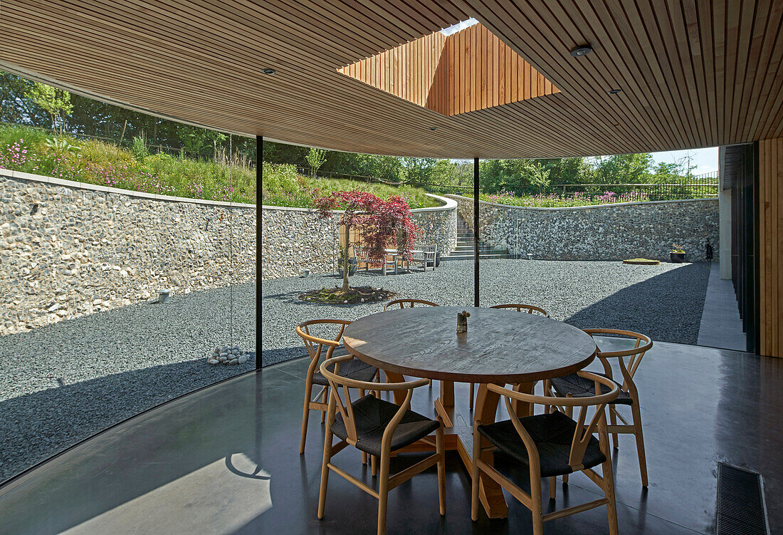 Runder Tisch mit Klassikerstühlen vor Verglasung im Architektenhaus