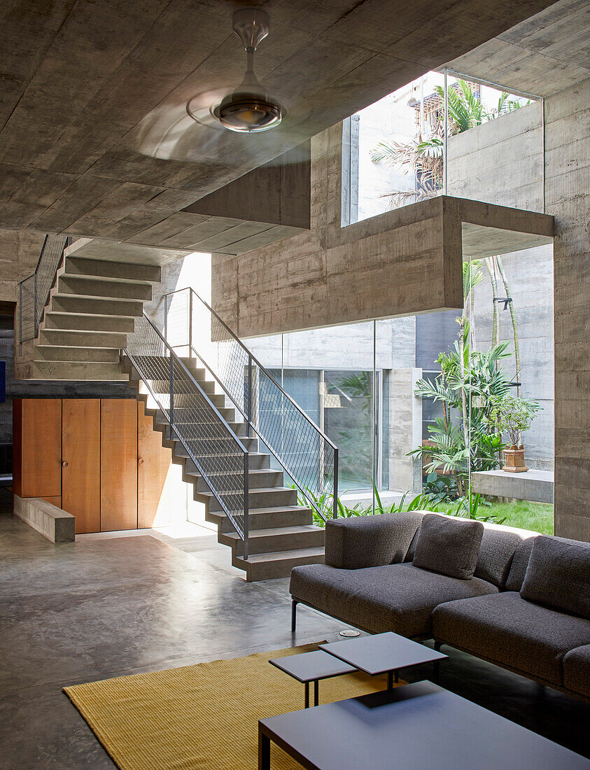 Sitzbereich im Erdgeschoss, Treppenaufgang zu Mezzanin in einem Betonhaus