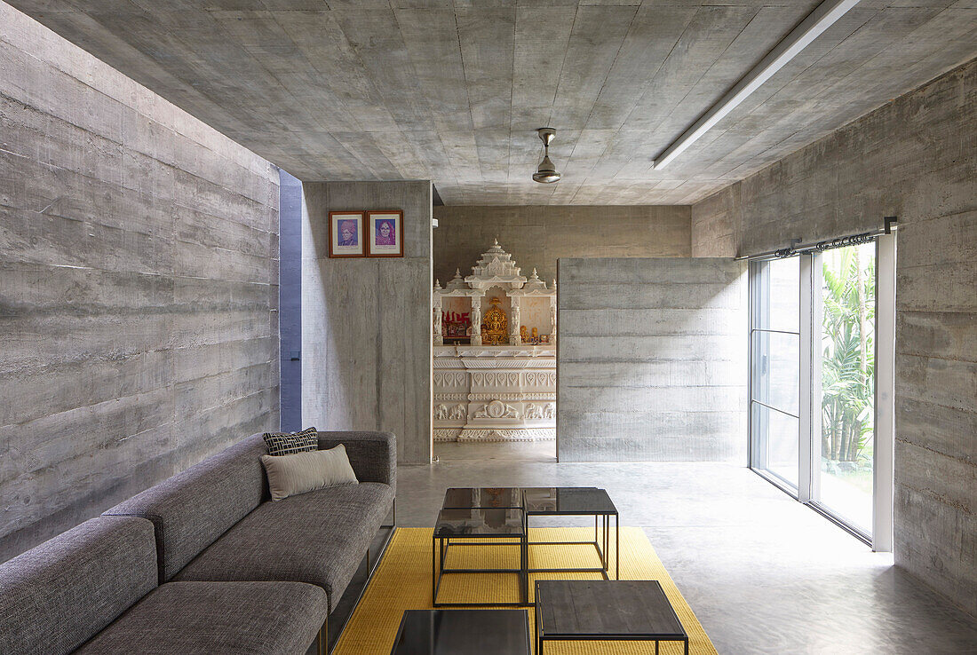 Sofa mit Tischset im Sitzbereich mit Terrassenzugang in einem Betonhaus