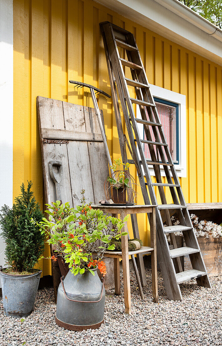 Alte Holz- und Zinkgegenstände entlang gelb gestrichener Holzwand von Bauernhaus