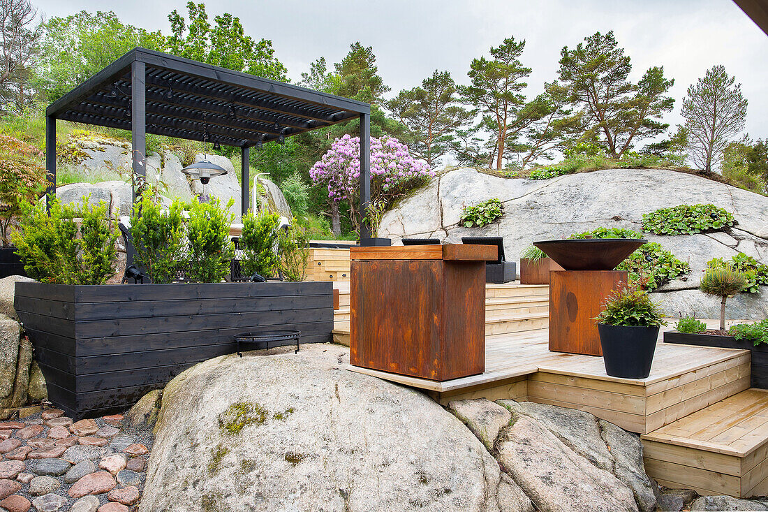 Mix of materials in the garden: large stones, wooden terrace and rusty Corten sheet metal