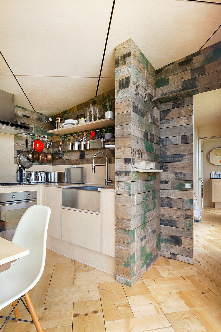 Kitchen with plywood cabinets and walls made of wooden crates, diamond-shaped ceiling with LED strips