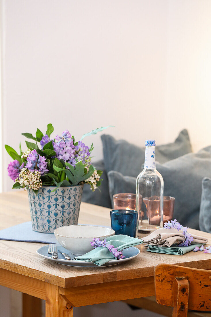 Bouquet of hyacinths (Hyacinthus) and snowball (Viburnum) in tin vase and breakfast crockery on kitchen table
