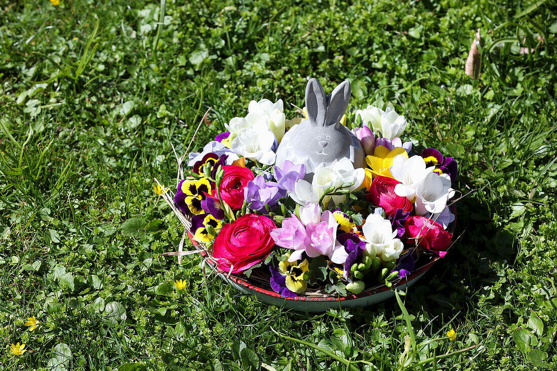 Flower bowl with Easter bunny figurine on grass