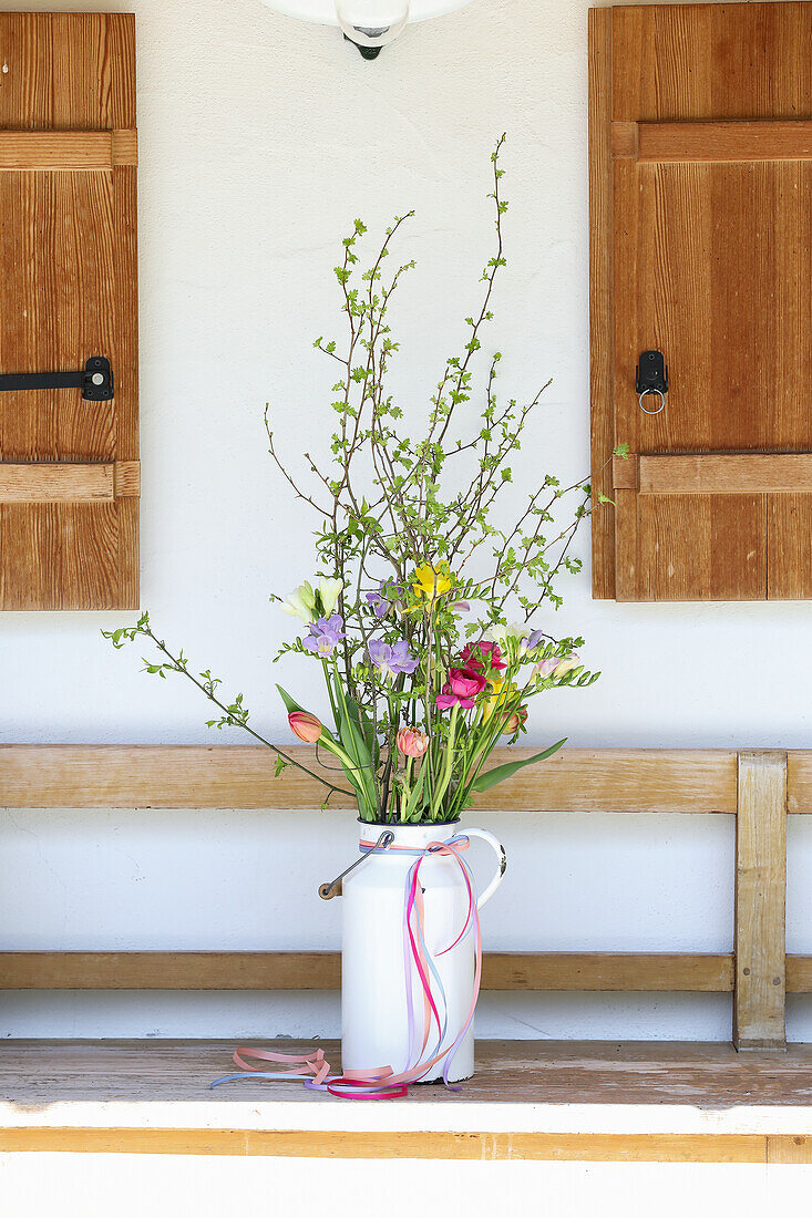 Spring bouquet of freesia and tulips (Tulipa) on a wooden bench