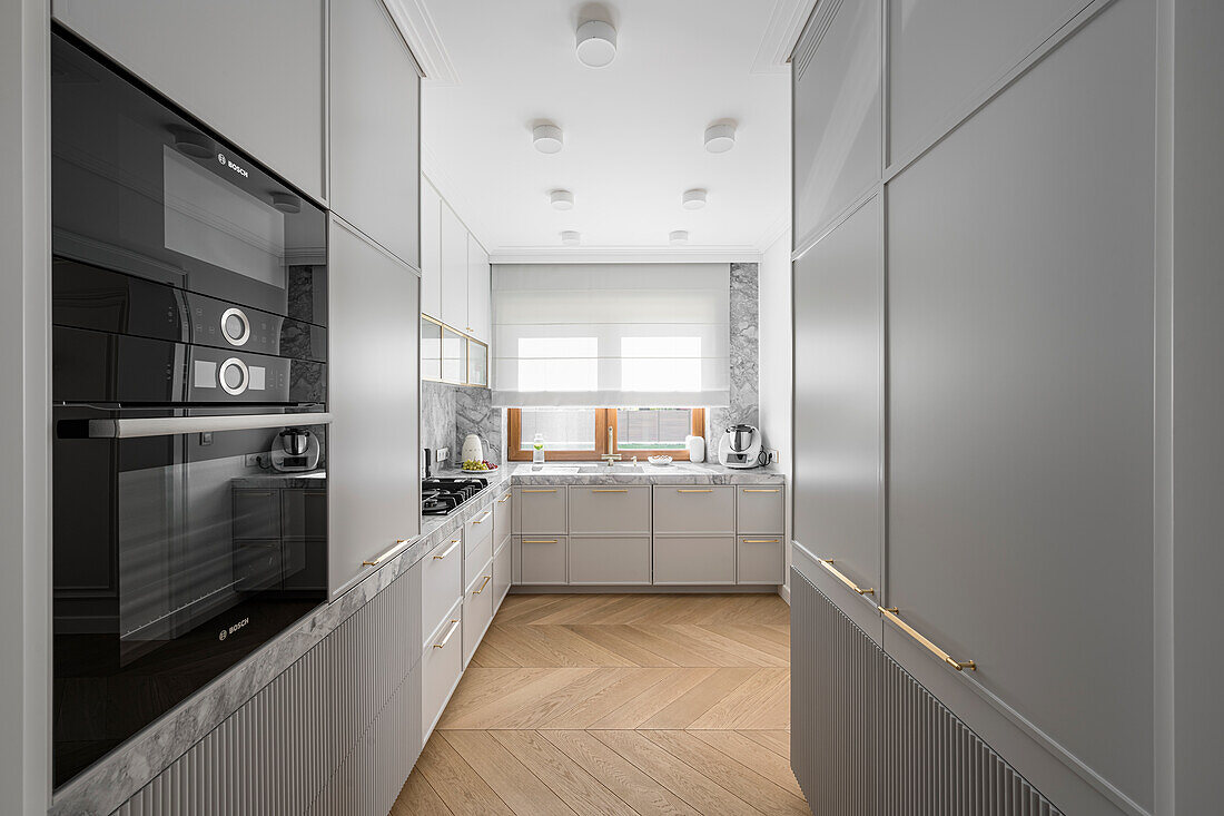 Moderne graue Küche mit Steinarbeitsplatte und geriffelten Schrankfronten