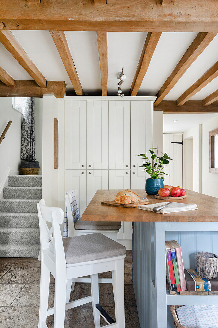 Country kitchen with light grey centre block and wooden beamed ceiling