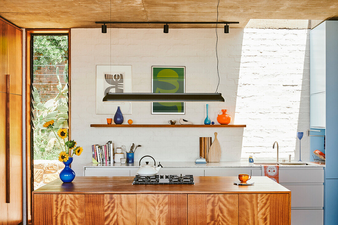 Kitchen island with wooden front and white kitchen cabinets in front of whitewashed brick wall