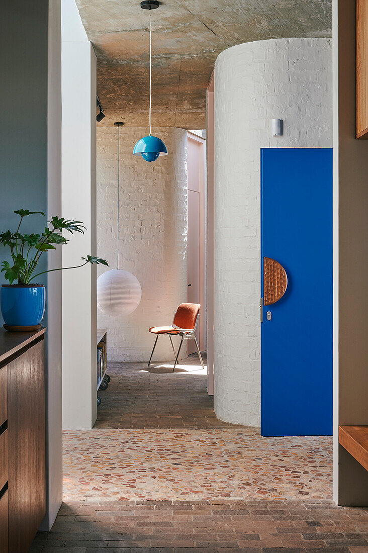 Curved white wall and blue door in entrance hall with stone floor