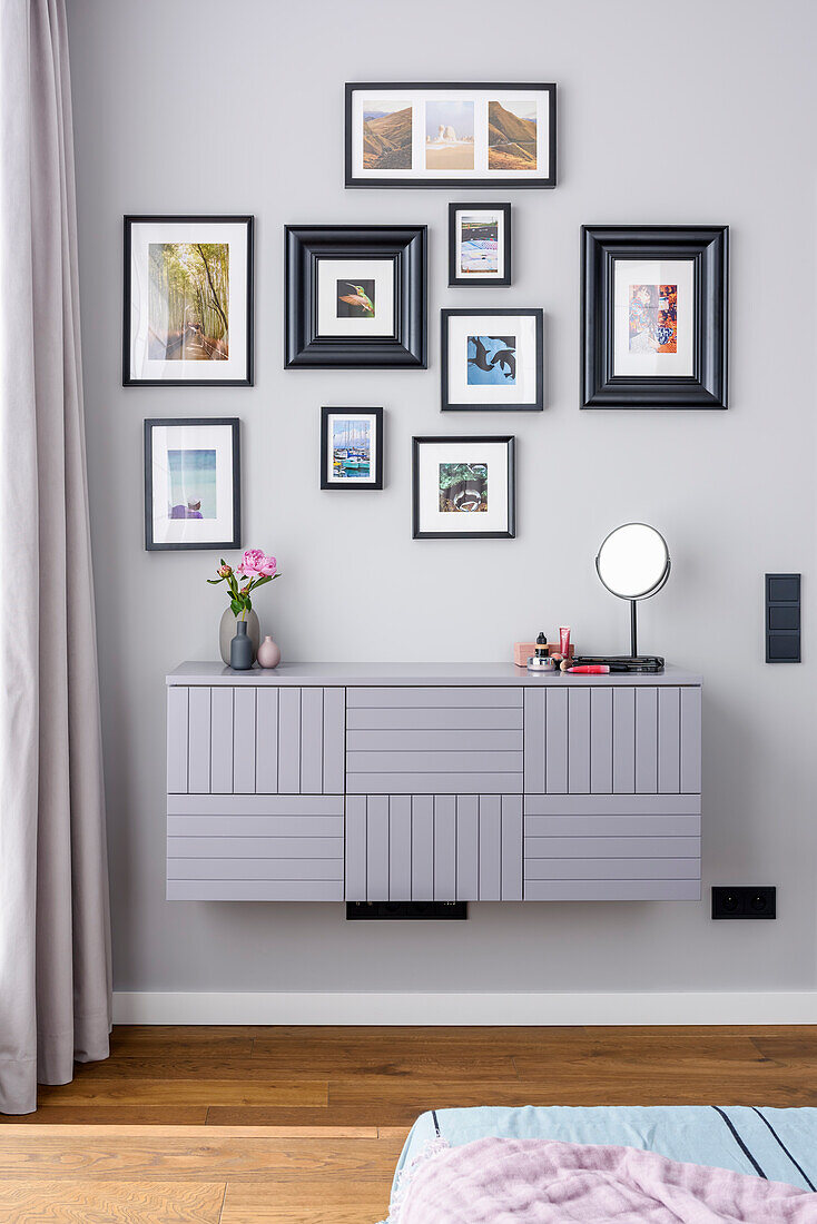Mounted dresser, above it photo gallery in the bedroom with pastel-colored wall