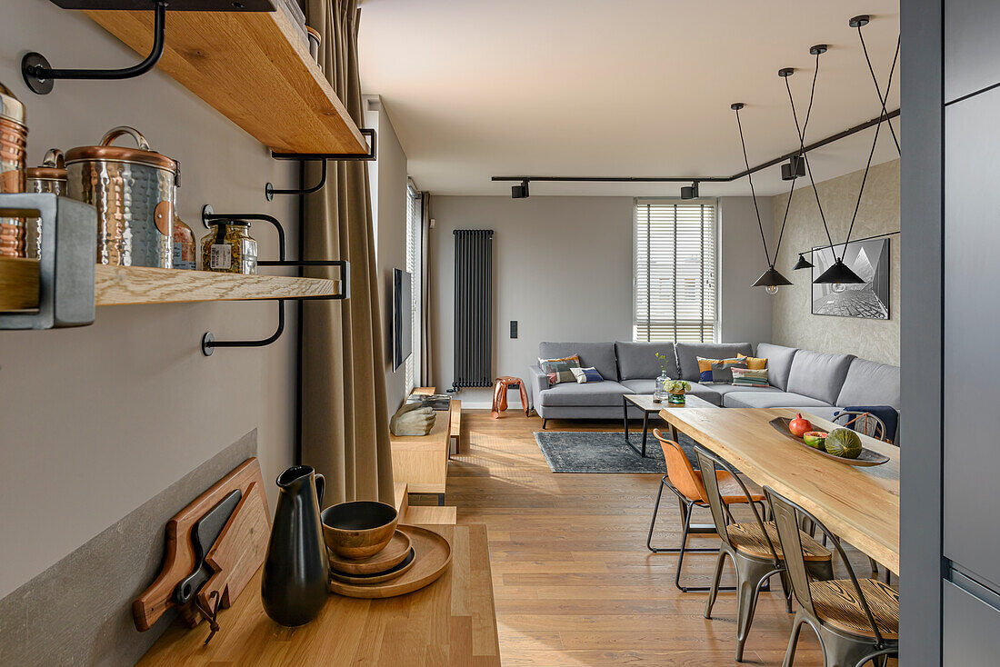 Offener Wohnraum mit Küche, Essbereich und Lounge in gedeckten Grautönen und Naturholz