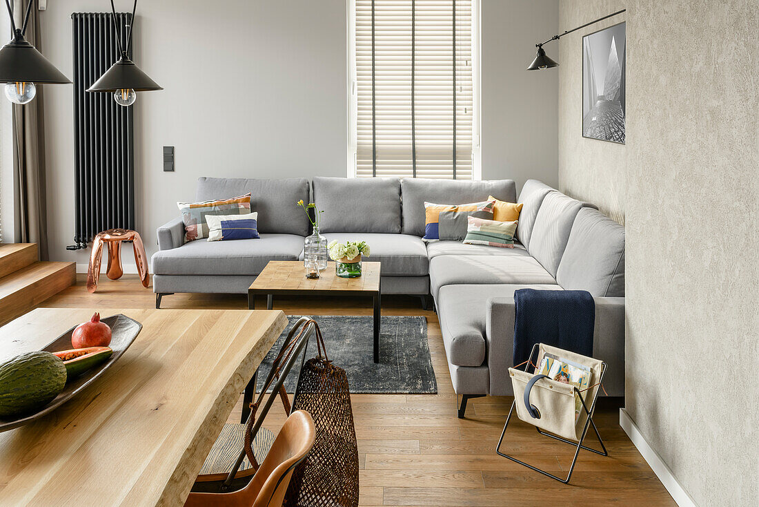 Offener Wohnraum mit Essbereich und Lounge in grauen Tönen, Wand in Betonoptik