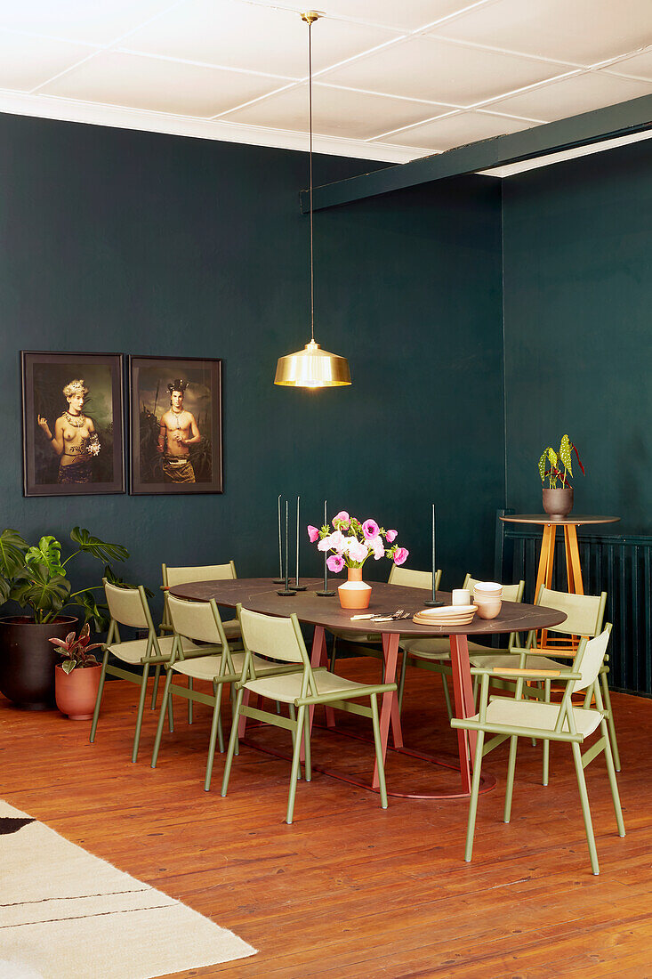 Dining table with light green chairs in a room painted dark blue