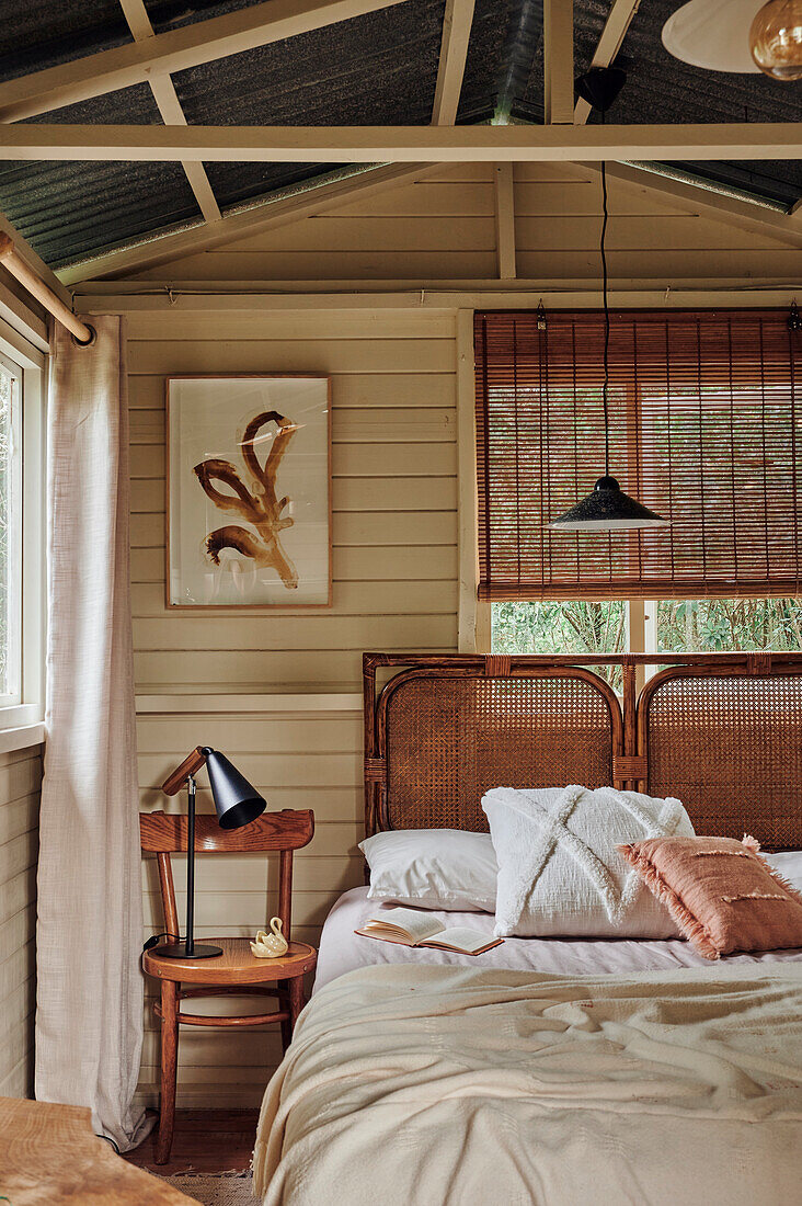 Double bed with rattan headboard in the guest room in earthy colors