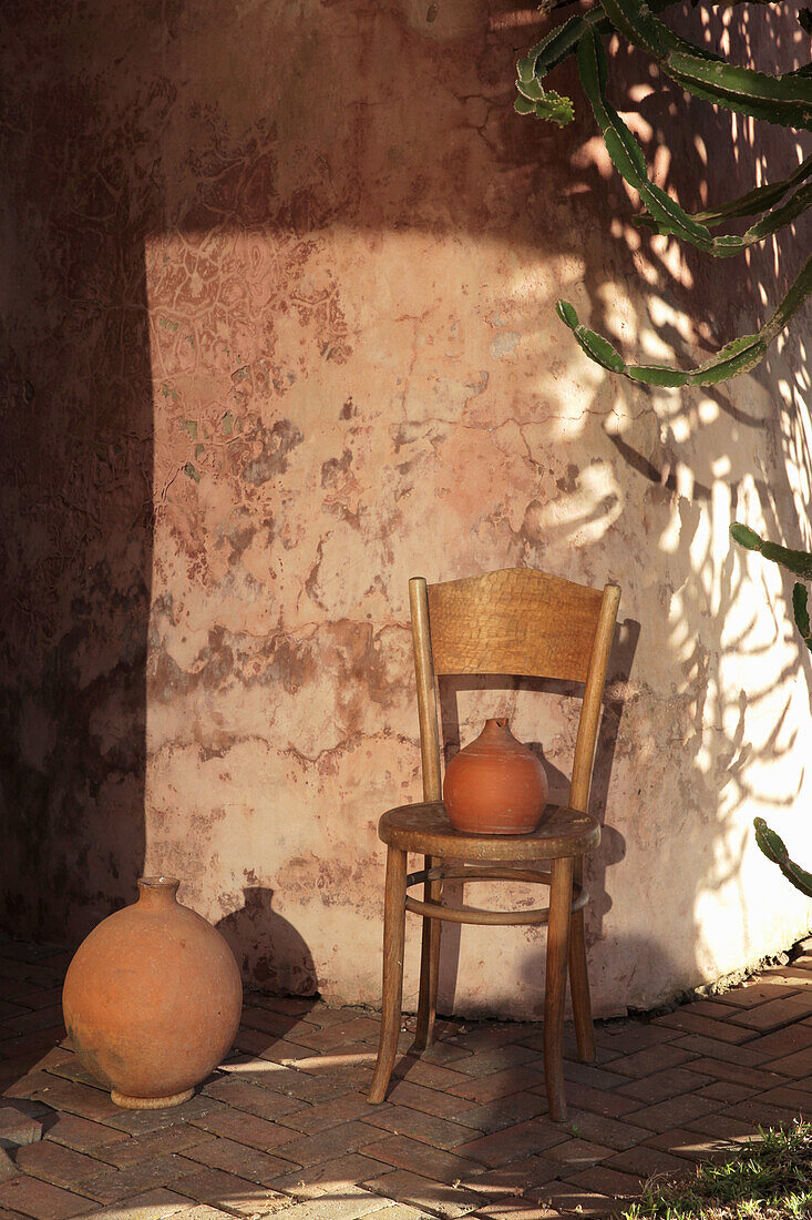 Wooden chair with clay pot in front of the house wall