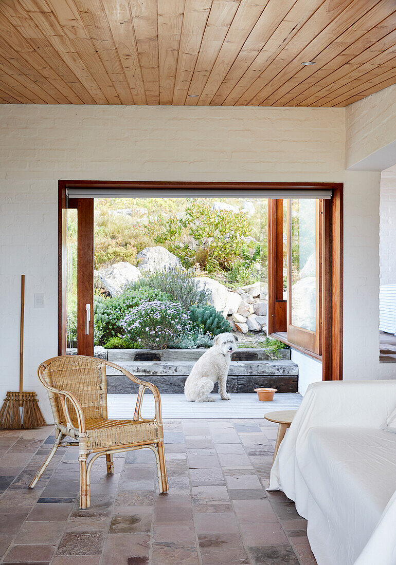 Lounge mit Rattanmöbeln, Kaminofen und Blick auf den Garten