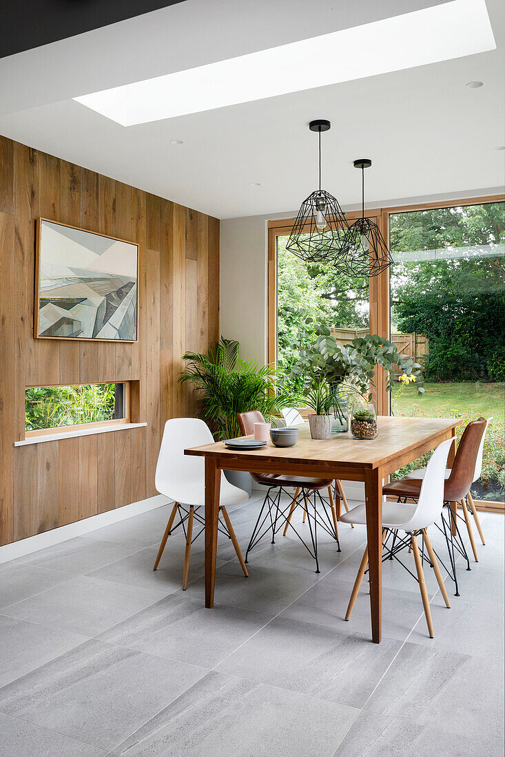 Bright dining area with skylight in front of oak plank wall paneling