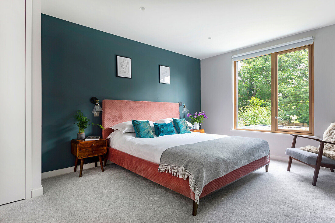 Spacious bedroom with double bed in front of dark teal wall
