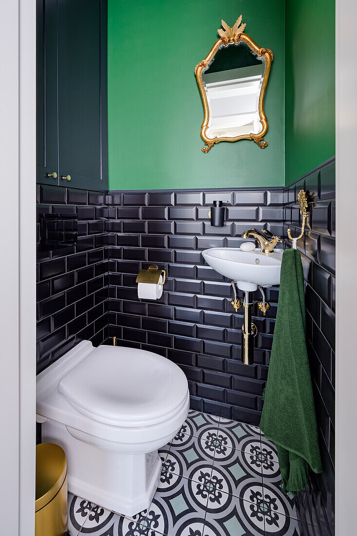 Small guest toilet, black subway tiles in the base area, green painted walls above it