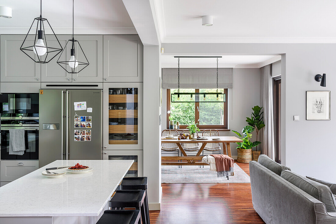 Weiß-graue Küche mit Kücheninsel, Blick ins Esszimmer und ins Wohnzimmer