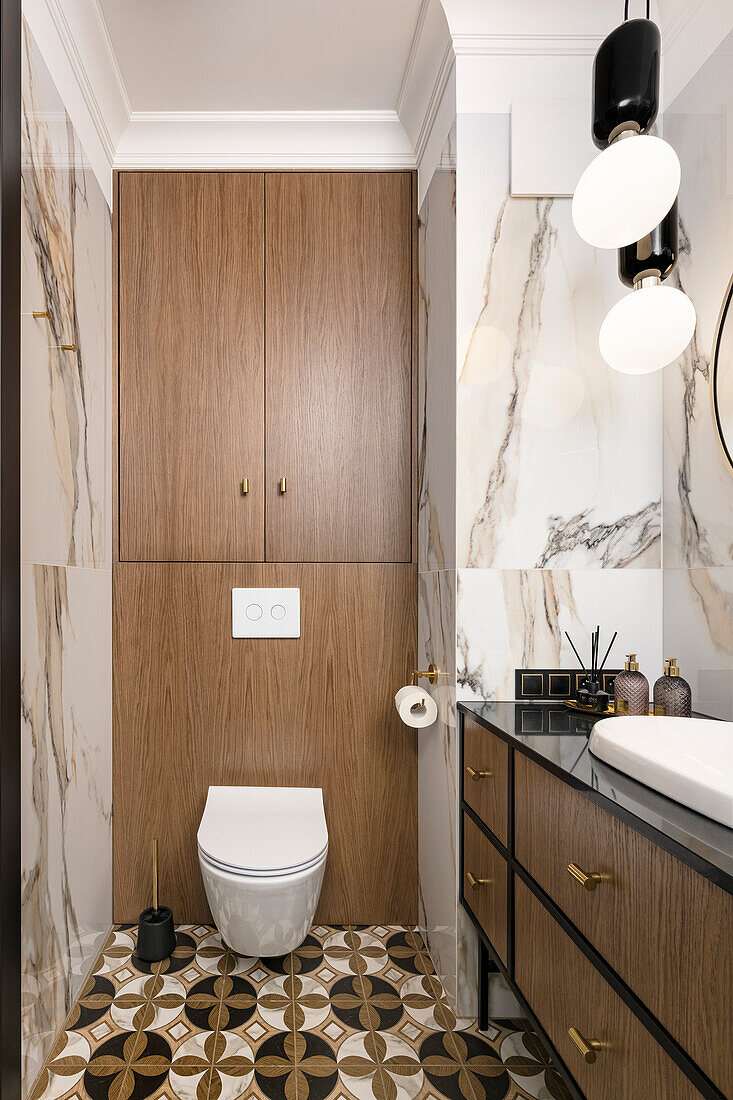 Bathroom, walls in white imitation marble tiles, toilet, and cabinet with wooden fronts