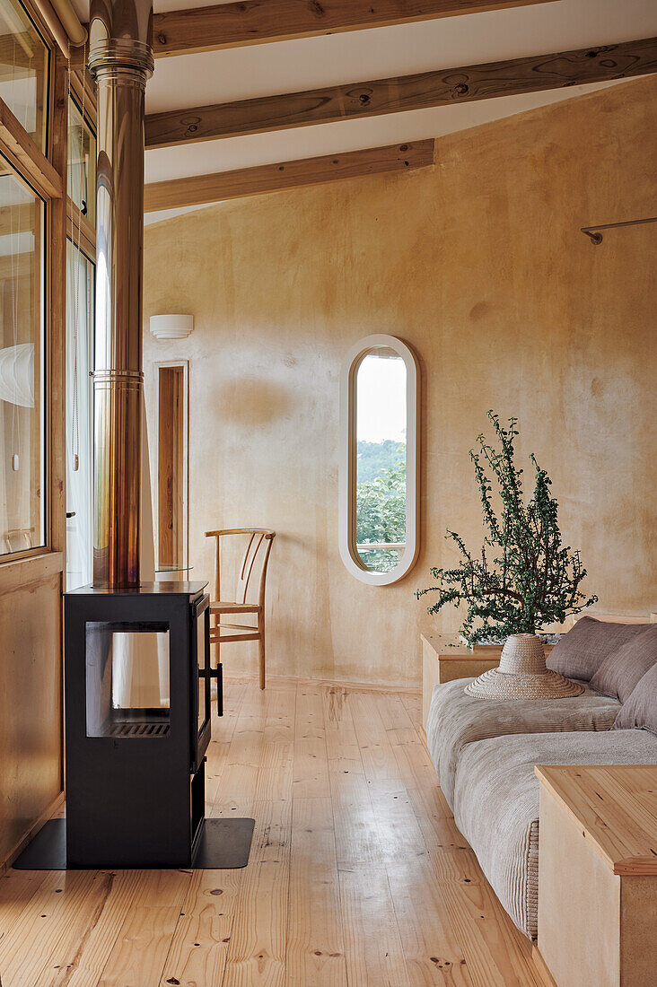 Heller Sitzbereich mit Sofa und Holzofen vor dem Fenster