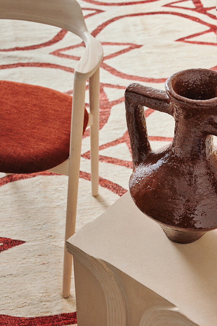 Keramikvase und Stuhl auf gemustertem Teppich