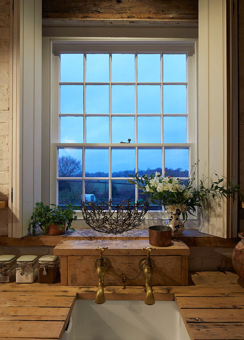 Rustikale Küche mit Holzarbeitsplatte, darüber Sprossenfenster mit Fensterladen