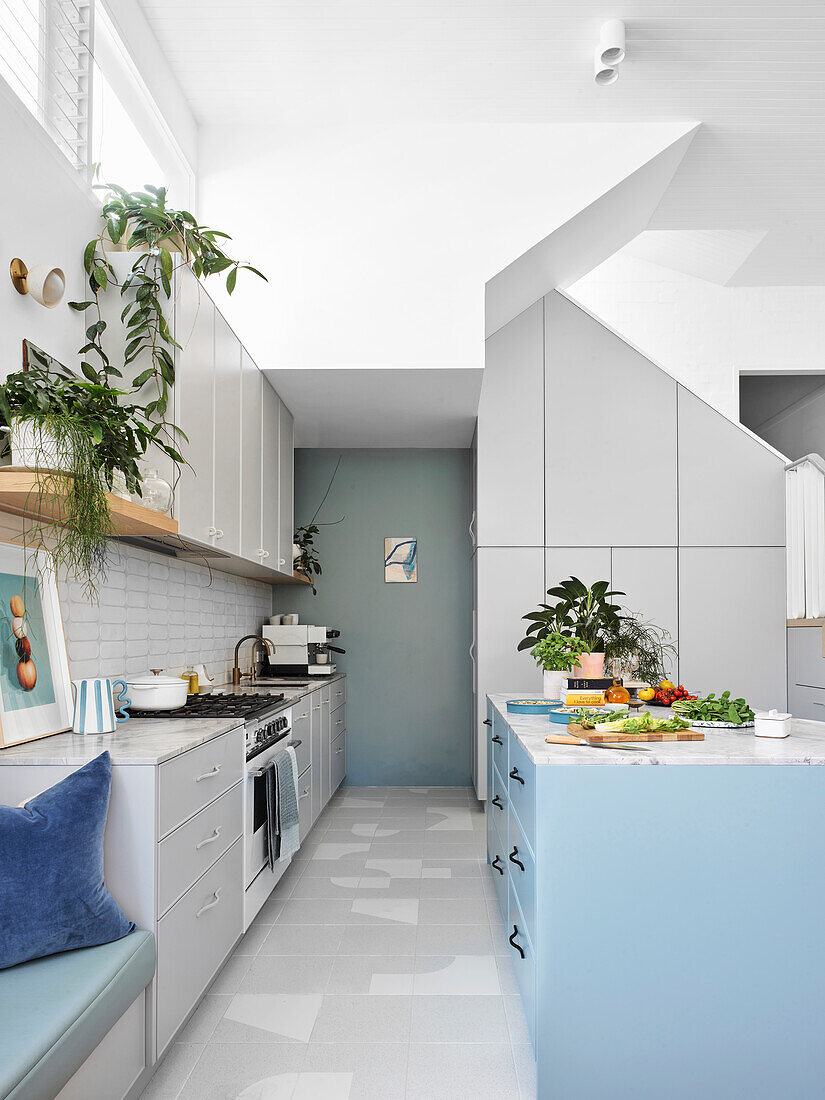 Offene weiße Küche mit hohen Decken und blauen Farbakzenten