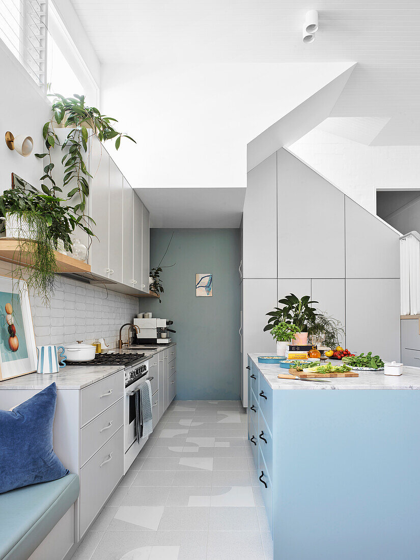 Open-plan white kitchen with high ceilings and blue color accents