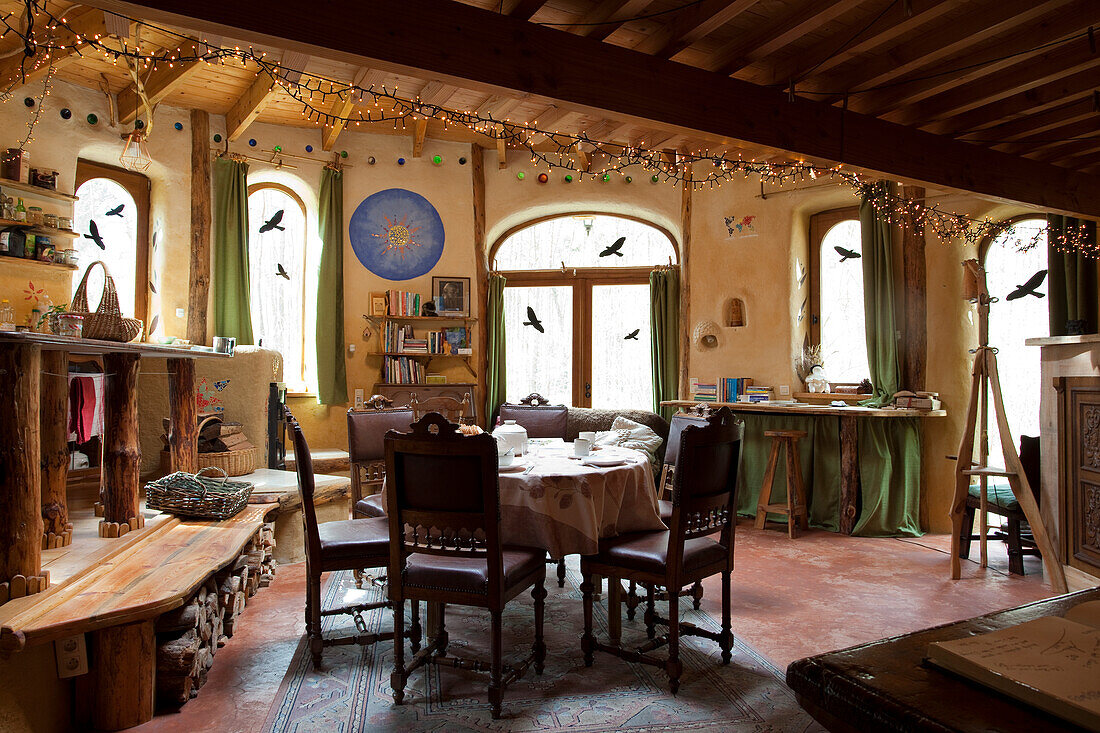 Round dining table, in the foreground wooden bench in rustic ambience with round arched windows