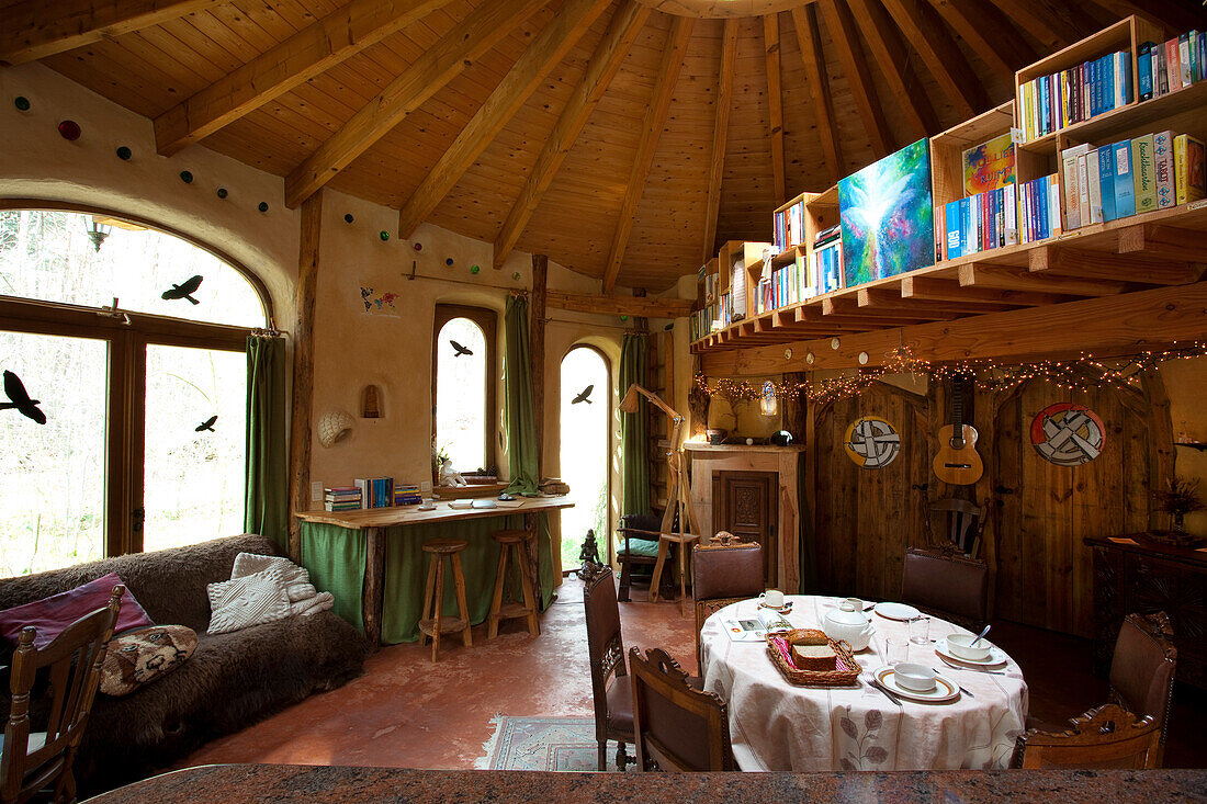 Round dining table, sofa, desk, and gallery bookcase in rustic ambience