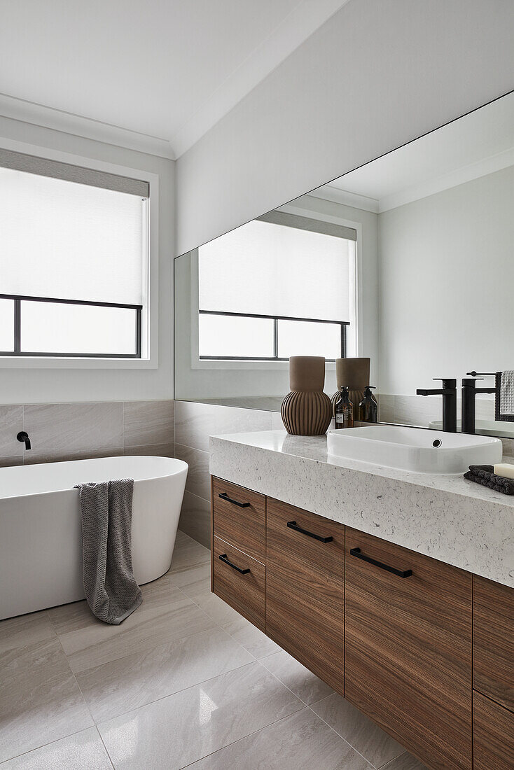Modern bathroom in neutral tones with freestanding bathtub and vanity unit