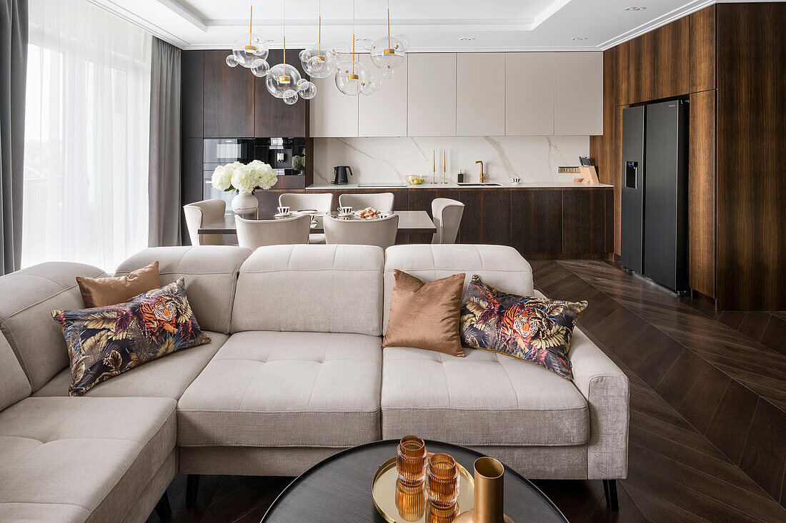 Polstersofa in kühlem Beige in offenem Wohnraum im Hampton-Stil, dunkelbraune Farbpalette mit goldenen Accessoires