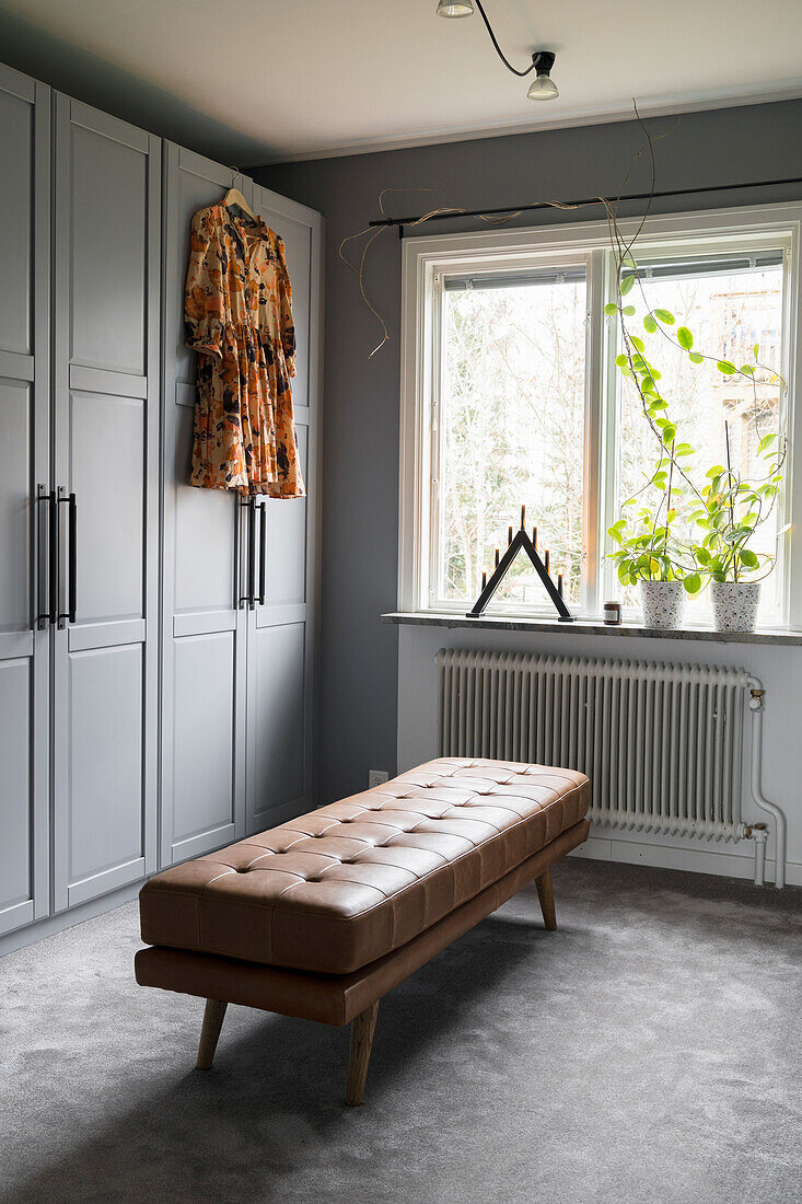 Elegant dressing room with upholstered bench and grey fitted wardrobes