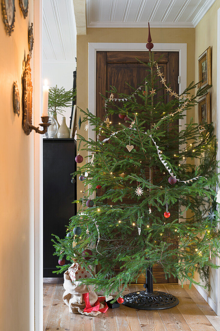 Weihnachtsbaum mit traditionellem Schmuck im Flur eines Wohnhauses