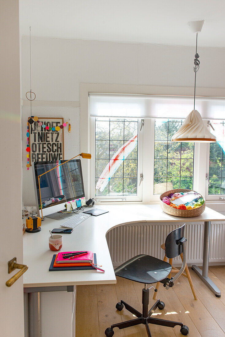 Heimisches Arbeitszimmer mit Schreibtisch, Computer und bunter Wanddekoration