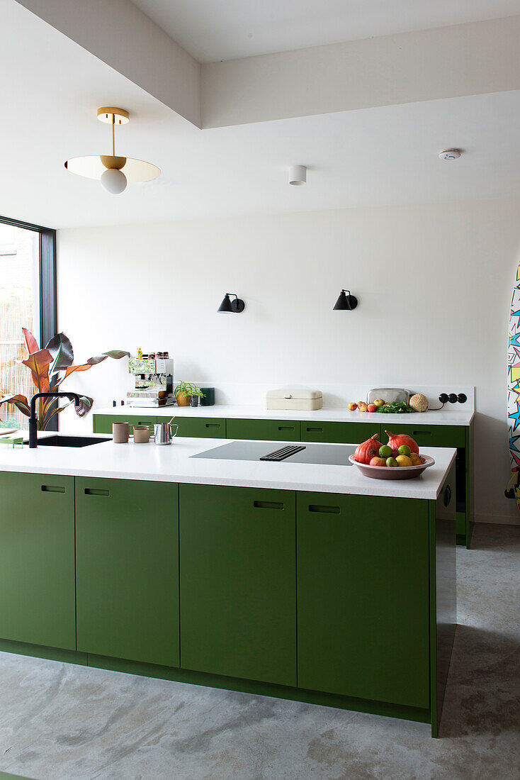 Modern kitchen with green base units and golden pendant light