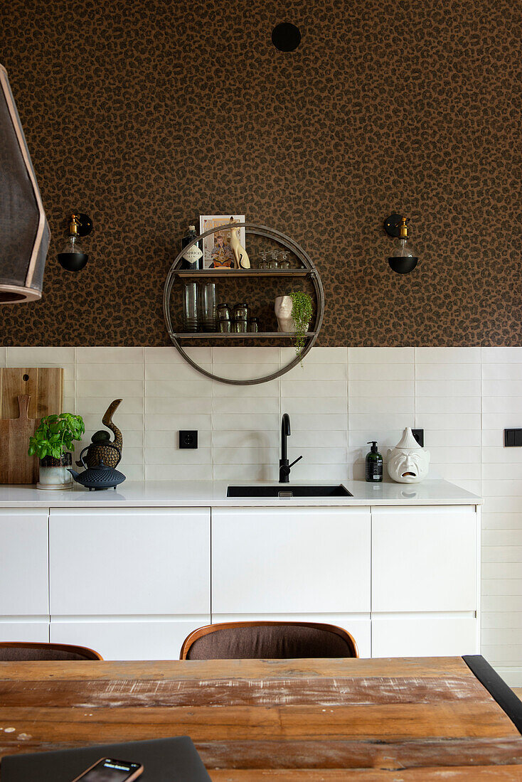 Kitchen with leopard wallpaper, black fittings and modern, round shelving unit