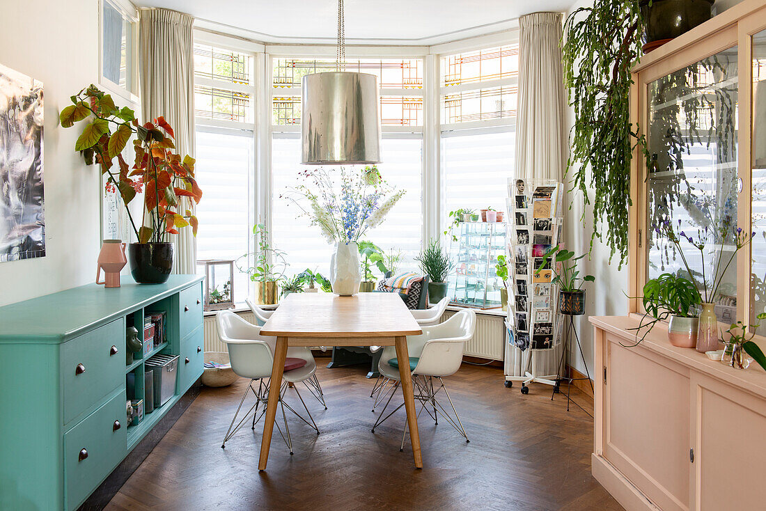 Bright dining area with mint-colored sideboard and houseplants